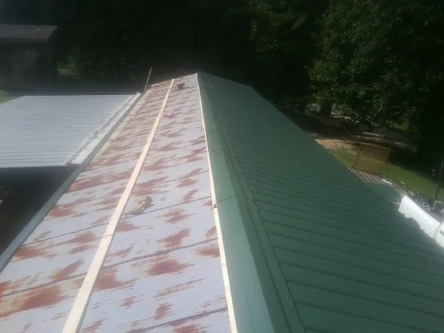 Old rusted panels beside newly installed green metal roofing — Wind Damage Roof Repair by Roofing Brothers in Sun City