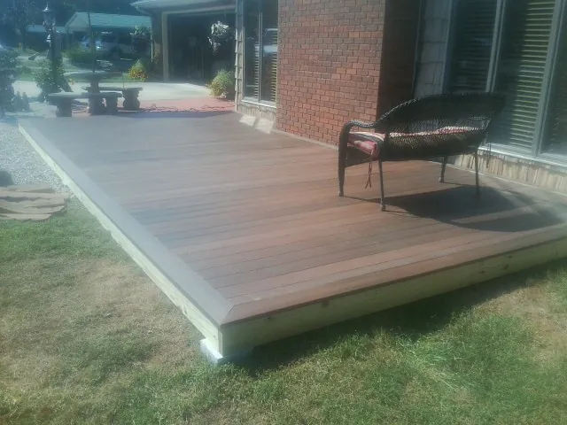 New wood deck and wicker chair beside a brick house in Sun City