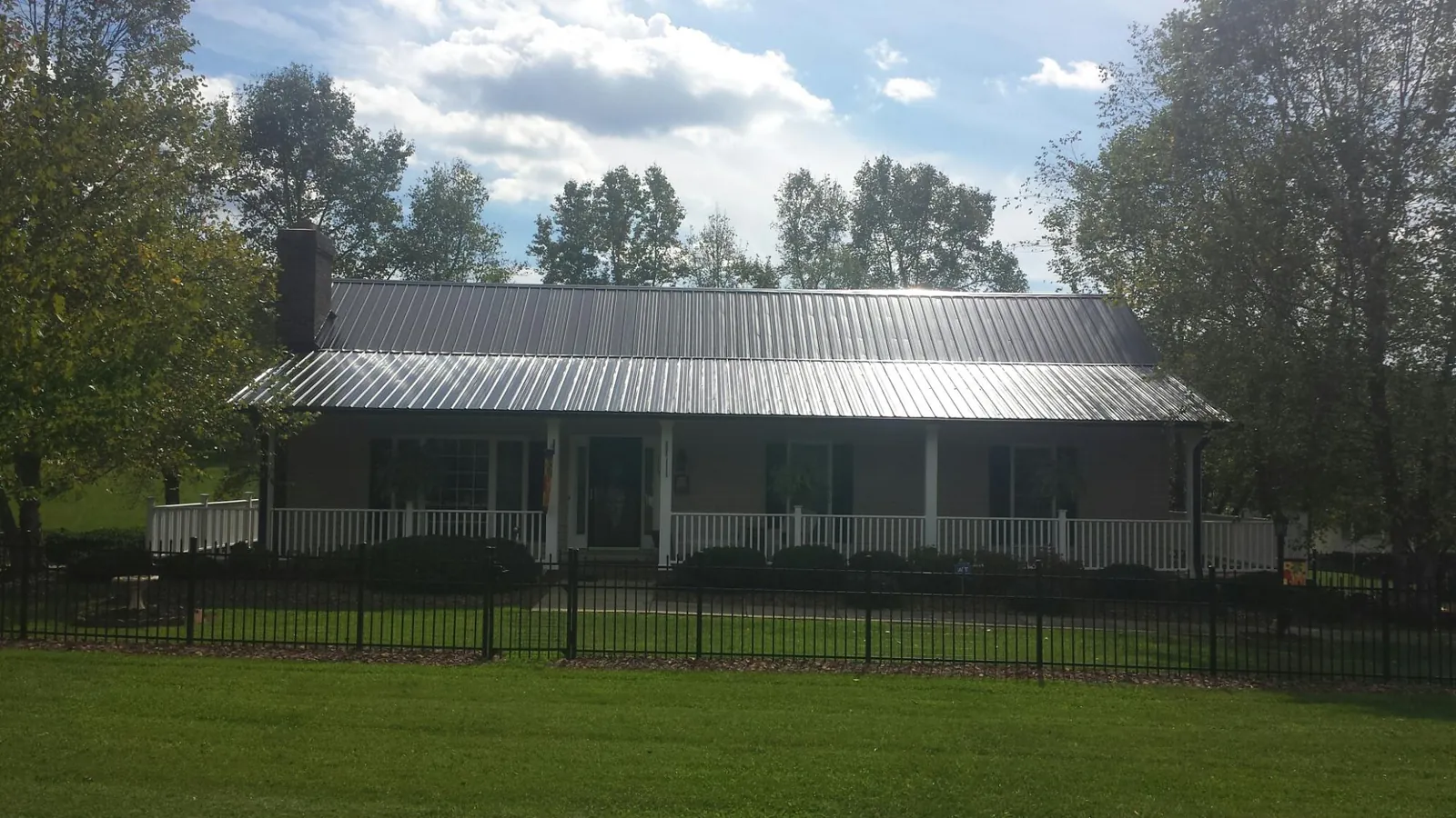 Gray metal roof on a brick ranch with a full width front porch — Gutter Guard Installation work by our crew in Sun City