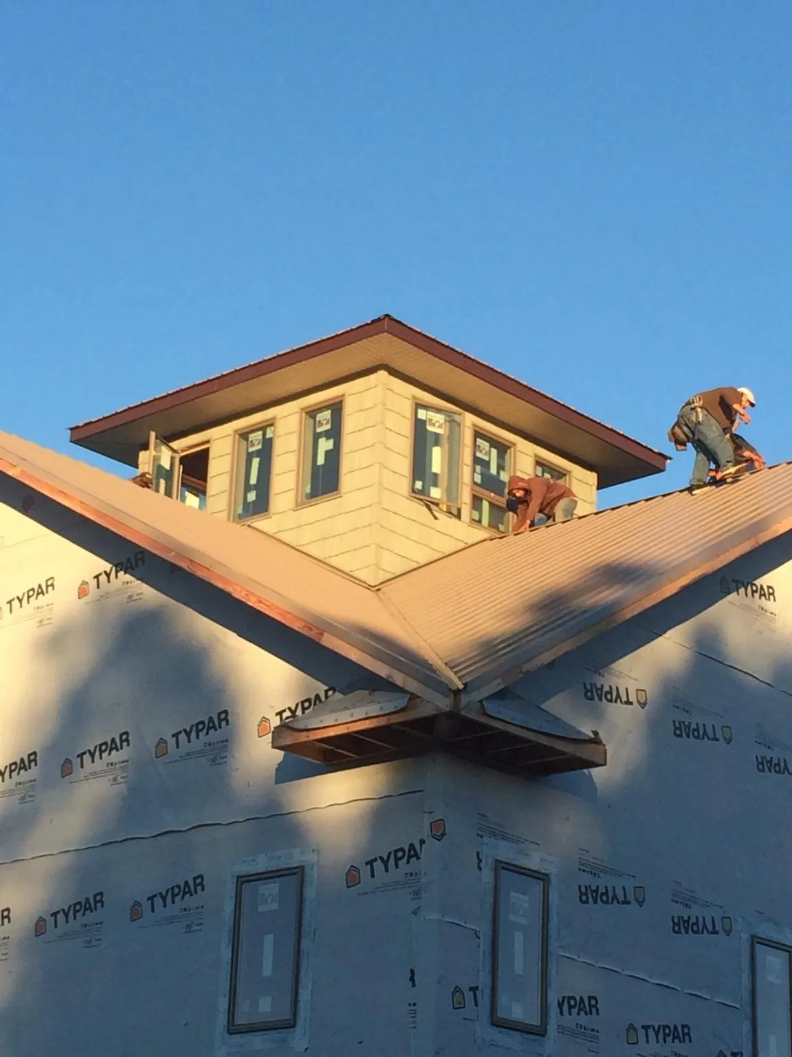 Roofers working around a rooftop cupola on a new metal roof at sunset — Roof Waterproofing in Sun City by Roofing Brothers